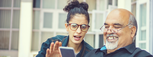 Daughter helping father with mobile device