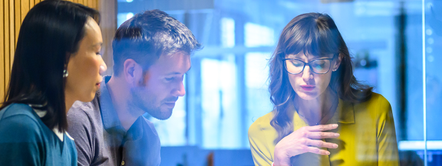 Three people in a meeting room reviewing information