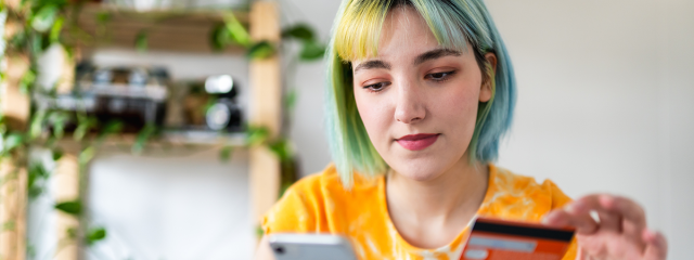Young person with card and phone making an online purchase