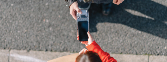Two people exchanging a point-of-sale payment outdoors.