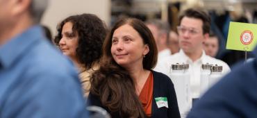 People sitting at a conference with a woman the focus of the image