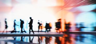 Silhouttes of people walking in front of a multicoloured background